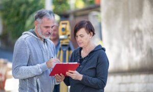 Two land surveyors reviewing boundary notes during an ALTA Land Title Survey to confirm property limits
