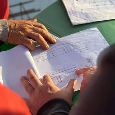 Land surveying team reviewing property boundary drawings and measurement notes