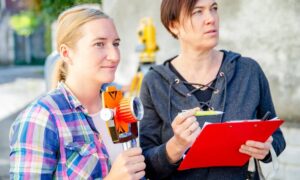 Surveyors reviewing measurements and equipment while performing a lot survey before new construction