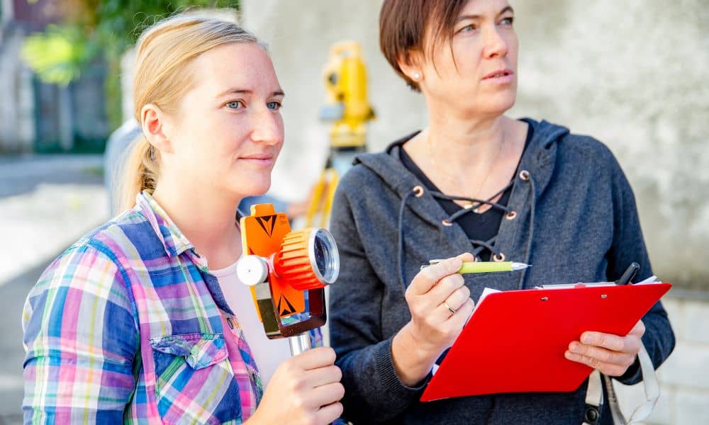 Surveyors reviewing measurements and equipment while performing a lot survey before new construction
