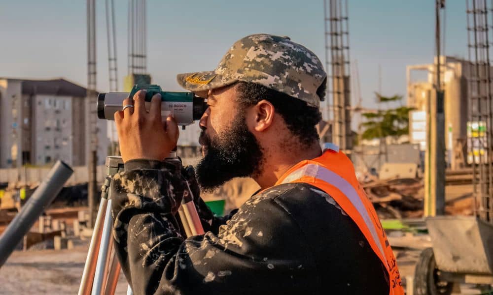 Construction staking survey indianapolis - ALTA SURVEY Indiana Surveyor using a tripod-mounted instrument on a construction site in Indianapolis performing construction staking surveys to ensure accurate layout for fast-paced projects