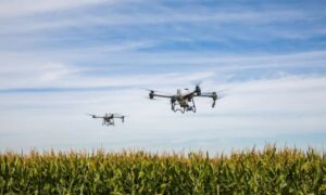 Drone surveying with two drones flying above farmland capturing aerial mapping data