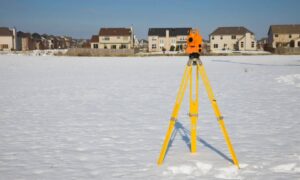 Total station used for a boundary line survey in a open field near residential properties