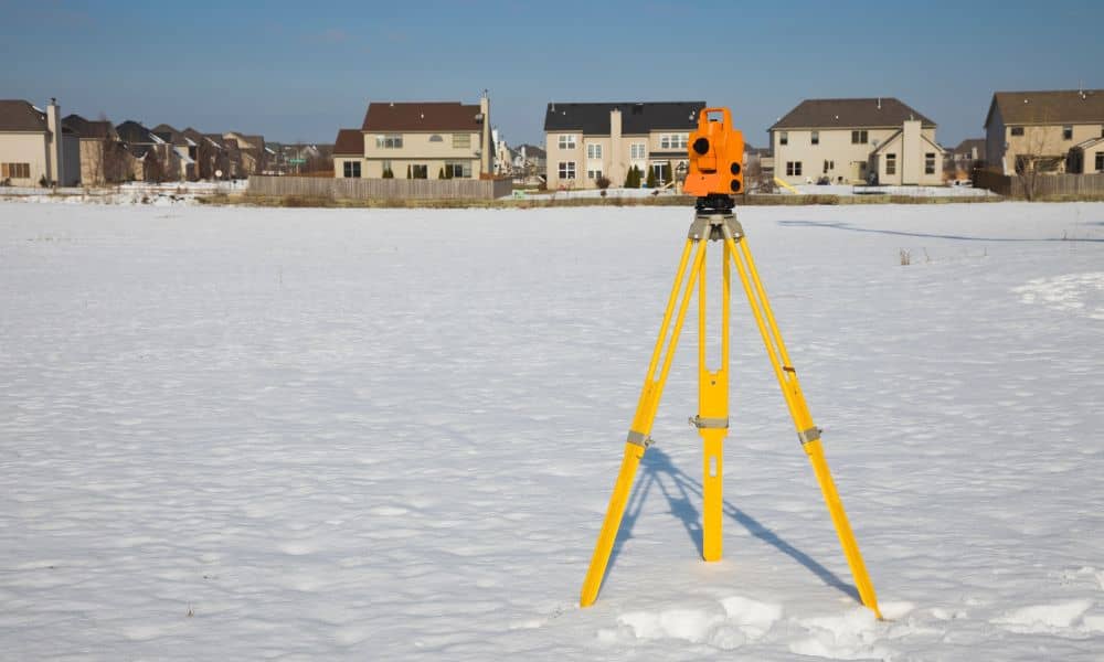 Boundary line surveying equipment on rural property - ALTA SURVEY Indiana Total station used for a boundary line survey in a open field near residential properties
