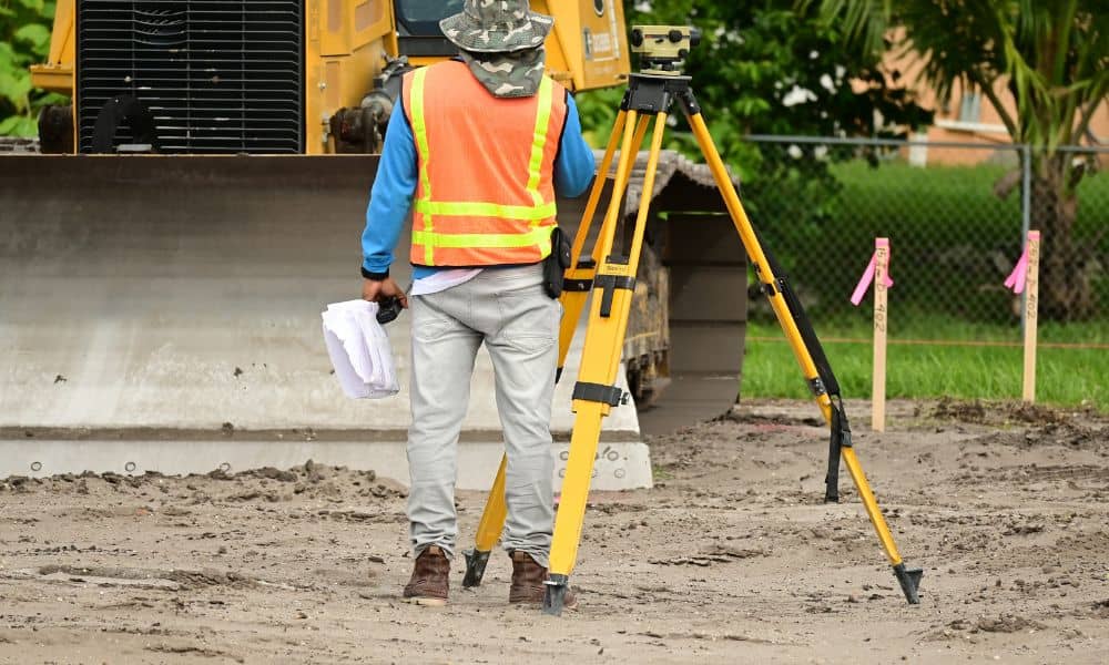 Surveying equipment residential site - ALTA SURVEY Indiana A surveyor setting up equipment and marking layout points during a construction survey on a residential job site