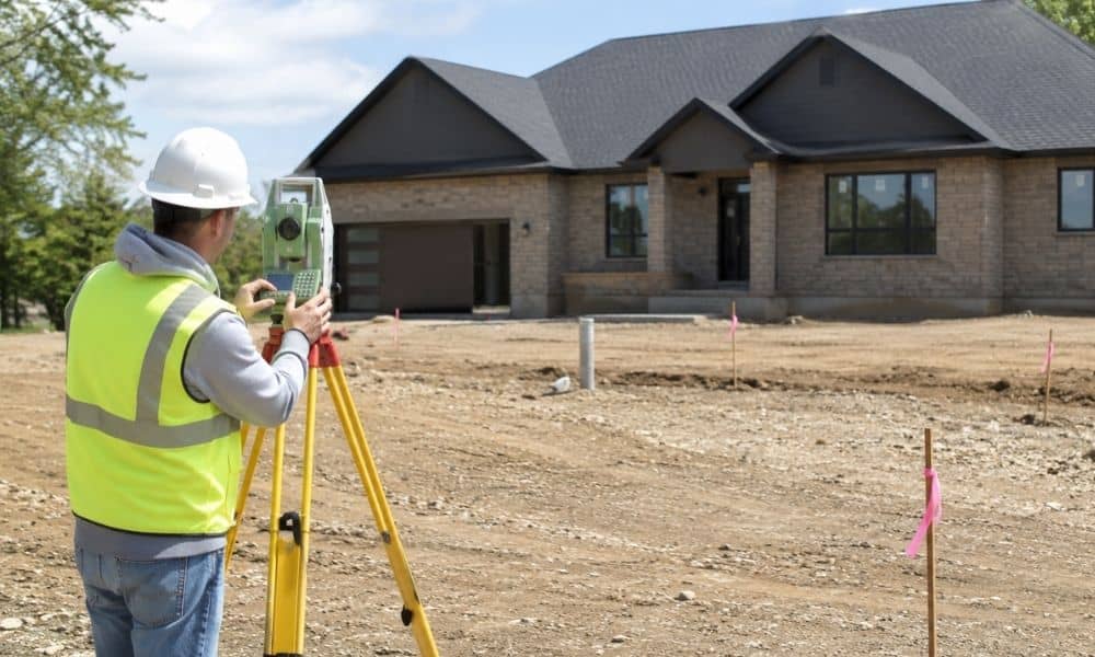 As built survey completed construction site - ALTA SURVEY Indiana Licensed land surveyor reviewing a newly completed construction site with survey equipment during an as-built survey inspection
